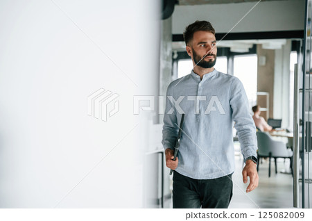 With laptop in hand. Young office worker in formal clothes is indoors 125082009
