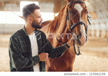 Young man with a horse is in the hangar 125082236
