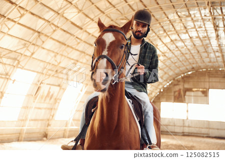 Riding the horse. Young man is in the hangar 125082515
