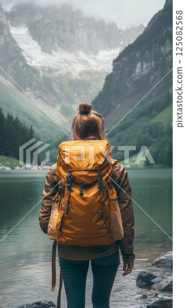 Girl traveler explores a serene hiking trail by a crystal-clear lake 125082568
