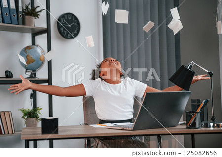 Throwing stickers up in the air. Celebrating success. Cute female african american student child is sitting by the laptop 125082656