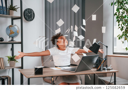 Throwing stickers up in the air. Celebrating success. Cute female african american student child is sitting by the laptop 125082659