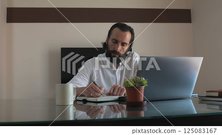 Confident Freelancer Working in Office with Laptop and Notebook 125083167