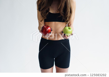 Sporty woman with perfect body holding green and red apples. Healthy low calorie meals, fresh fruits Sporty woman with perfect body holding green and red apples. Healthy low calorie meals, fresh fruits 125083202