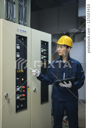 圖為大樓維修人員手持平板電腦檢查大樓的電氣設備 125083410