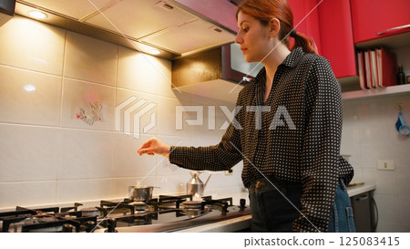 In a Small Kitchen A Woman Soaks A Tea Bag In The Pan 125083415