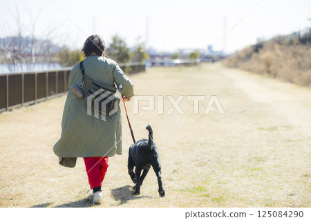 A woman walking a dog A woman walking a dog 125084290