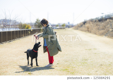 A woman walking a dog 125084291