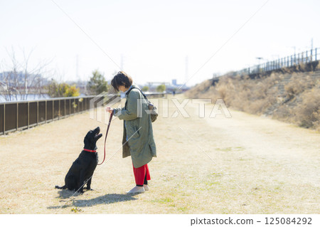 A woman walking a dog 125084292