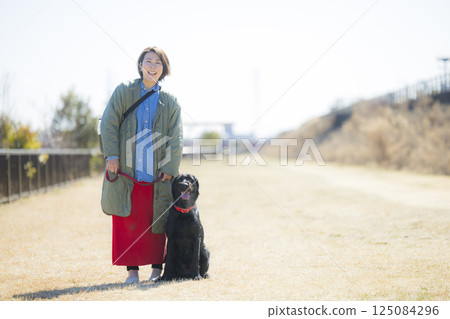 A woman walking a dog 125084296