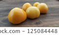 Five yellow tomatoes on a wooden table 125084448