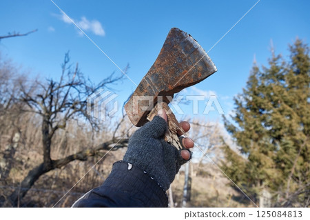 Broken axe held up in hand in the backyard 125084813