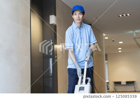 男性清潔人員與商用地毯吸塵器一起工作 男性清潔人員與商用地毯吸塵器一起工作 125085339
