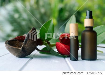 Two elegant cosmetic bottles with a pipette are placed on a wooden surface surrounded by greenery. Two elegant cosmetic bottles with a pipette are placed on a wooden surface surrounded by greenery. 125085777