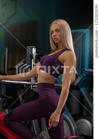 fitness model showcases her strength and style in a purple workout outfit while posing in a well equipped gym. The atmosphere is vibrant and energetic. fitness model showcases her strength and style in a purple workout outfit while posing in a well equipped gym. The atmosphere is vibrant and energetic. 125085936