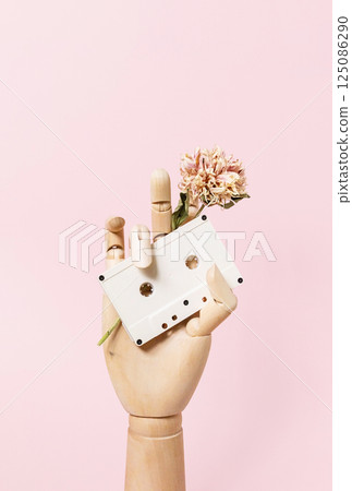 Vintage Vibes in Mannequin Hand Holding Retro Audio Cassette with Withering Flower. Vintage Vibes in Mannequin Hand Holding Retro Audio Cassette with Withering Flower. 125086290