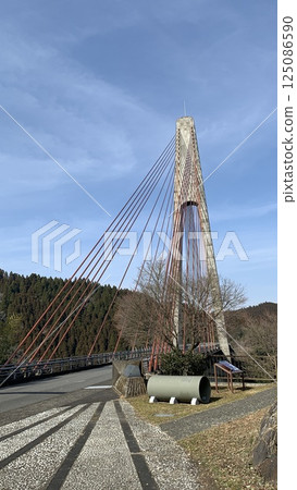A white suspension bridge shining against the blue sky 125086590