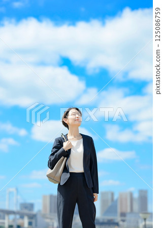 Business woman standing with blue sky in the background Business woman standing with blue sky in the background 125086759