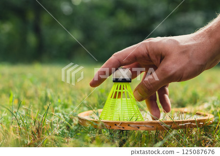 Neon yellow badminton shuttlecock and racket on green grass outdoors. Copy space soft selective focus on shuttlecocks. Alternative fitness recreational 125087676