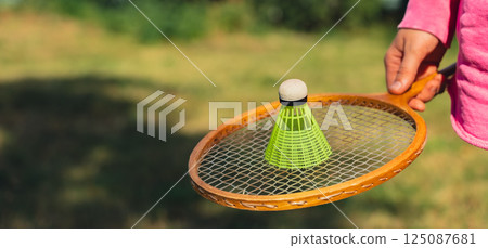 Woman hand holding wooden Badminton racket and shuttlecock. Outside recreation and fresh air. Healthy lifestyle nature connection sport summer activities. Stress relief hobby 125087681