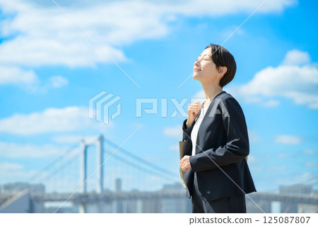 Business woman standing with blue sky in the background 125087807