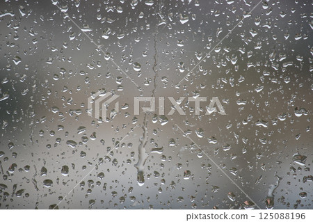 A close-up view of raindrops creating an artistic pattern on a window, a rainy day. A close-up view of raindrops creating an artistic pattern on a window, a rainy day. 125088196