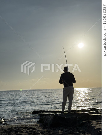 silhouette of a fisherman at sea sunset calm. High quality photo 125088387