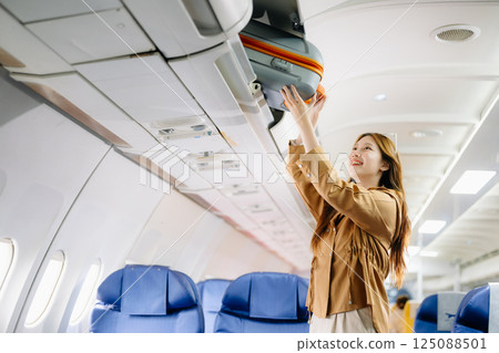 Smiling woman in first-class airplane seat, showcasing luxury, comfort, and elegance in travel. 125088501