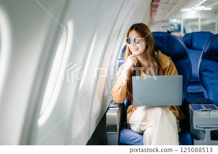 Smiling woman in first-class airplane seat, showcasing luxury, comfort, and elegance in travel. Smiling woman in first-class airplane seat, showcasing luxury, comfort, and elegance in travel. 125088513
