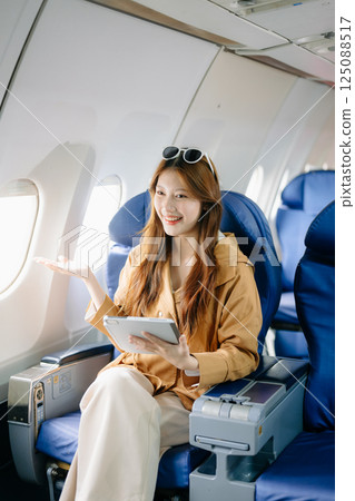 Smiling woman in first-class airplane seat, showcasing luxury, comfort, and elegance in travel. 125088517