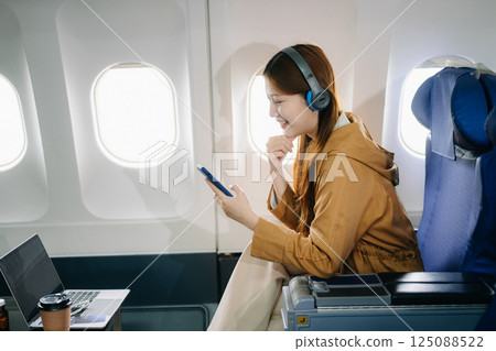 Smiling woman in first-class airplane seat, showcasing luxury, comfort, and elegance in travel. Smiling woman in first-class airplane seat, showcasing luxury, comfort, and elegance in travel. 125088522