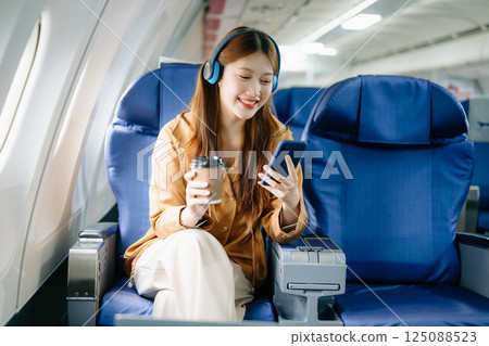 Smiling woman in first-class airplane seat, showcasing luxury, comfort, and elegance in travel. 125088523