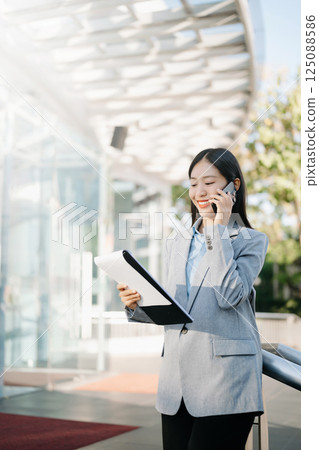 Asian business woman leader entrepreneur, professional manager holding digital tablet computer uon the street in big city on business center background. 125088586