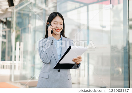 Asian business woman leader entrepreneur, professional manager holding digital tablet computer uon the street in big city on business center background. Asian business woman leader entrepreneur, professional manager holding digital tablet computer uon the street in big city on business center background. 125088587