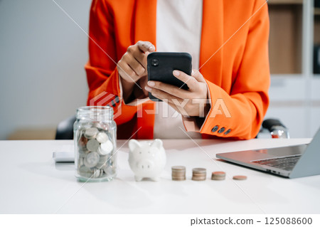 businesswoman holding coins putting in glass with using smartphone and calculator to calculate concept saving money 125088600