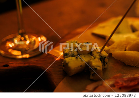 Delicacies served on a rustic wooden platter in an intimate dining setting with warm lighting Delicacies served on a rustic wooden platter in an intimate dining setting with warm lighting 125088978