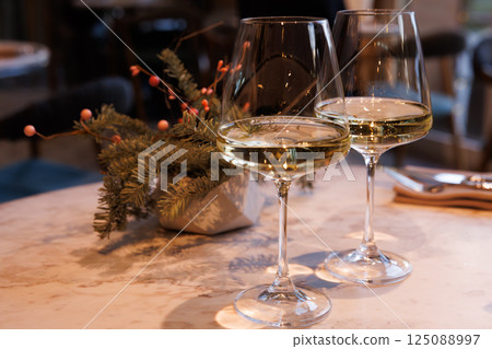 Enjoying elegant white wine in a cozy restaurant setting with greenery and soft lighting Enjoying elegant white wine in a cozy restaurant setting with greenery and soft lighting 125088997