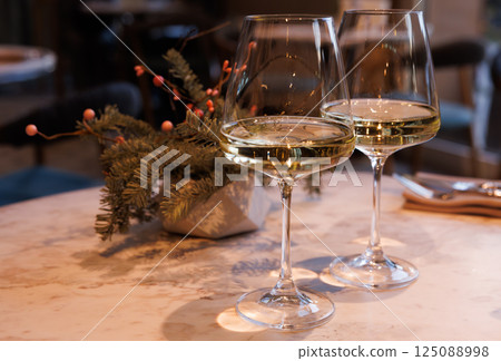 Elegant dining experience with summer white wines and floral arrangement in a cozy restaurant setting 125088998