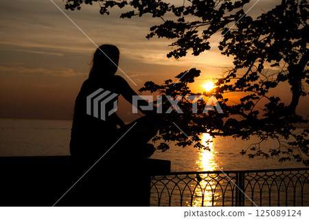 Sunset reflections over Bodensee with silhouetted figure enjoying tranquil moment by the water Sunset reflections over Bodensee with silhouetted figure enjoying tranquil moment by the water 125089124