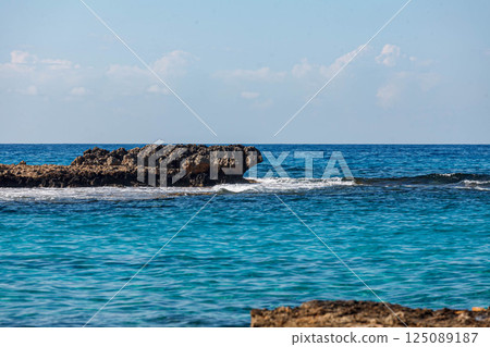 Crystal clear waters lapping against rocky shores in Ayia Napa, Cyprus on a sunny day 125089187