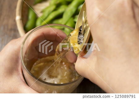 Pouring canned beer into a glass by hand Pouring canned beer into a glass by hand 125089791