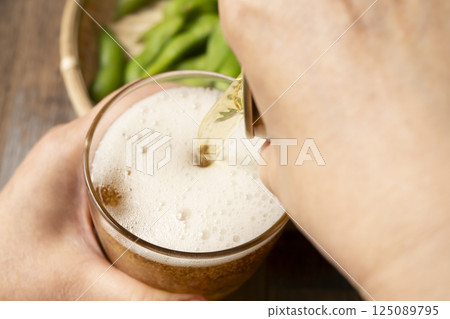 Pouring canned beer into a glass by hand Pouring canned beer into a glass by hand 125089795