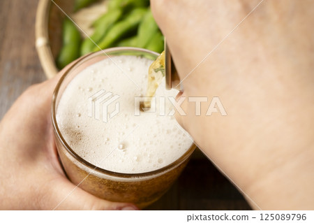 Pouring canned beer into a glass by hand Pouring canned beer into a glass by hand 125089796