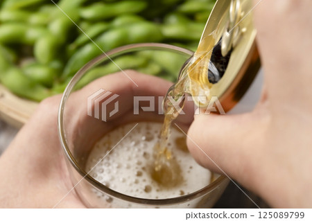 Pouring canned beer into a glass by hand Pouring canned beer into a glass by hand 125089799