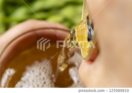 用手將罐裝啤酒倒入玻璃杯中 用手將罐裝啤酒倒入玻璃杯中 125089810