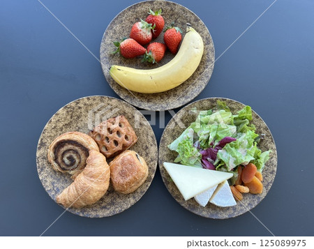 A set of bread, salad and fruit served on a mottled brown plate on a blue-grey background A set of bread, salad and fruit served on a mottled brown plate on a blue-grey background 125089975