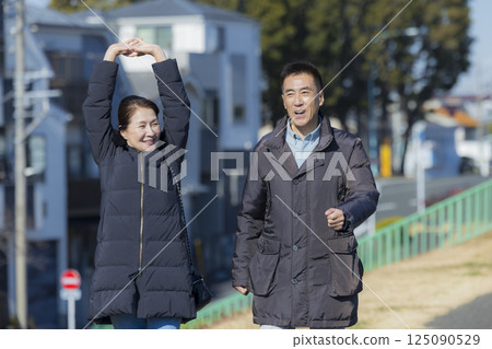 A middle-aged couple wearing coats taking a walk 125090529