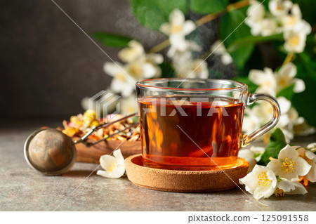 Jasmine tea and fresh jasmine flowers on a stone table. 125091558