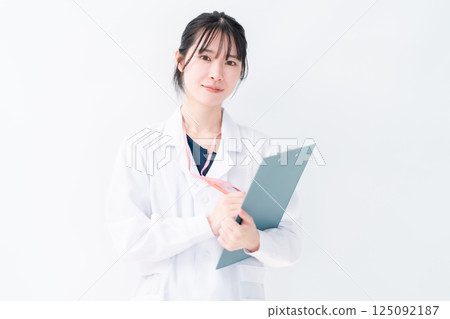 A female doctor in a white coat holding a file, white background A female doctor in a white coat holding a file, white background 125092187
