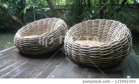 A beautifully designed chair made of woven rattan in a round shape placed in the garden A beautifully designed chair made of woven rattan in a round shape placed in the garden 125092303